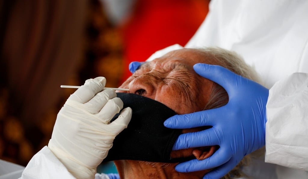 Healthcare workers take a coronavirus swab sample from a vendor at a traditional market in Bogor, West Java province, Indonesia. Photo: Reuters