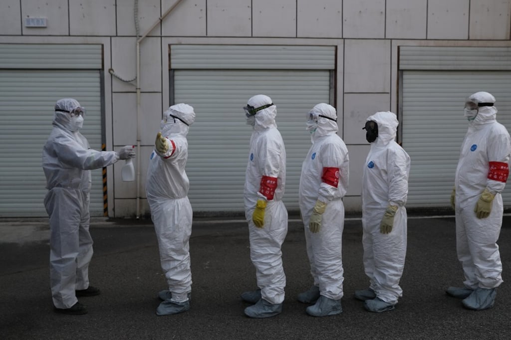 Volunteers in protective suits line up to be sprayed with disinfectant in Wuhan, the epicentre of the novel coronavirus outbreak, in February. Photo: Reuters Volunteers in protective suits line up to be sprayed with disinfectant in Wuhan, the epicentre of the novel coronavirus outbreak, in February. Photo: Reuters