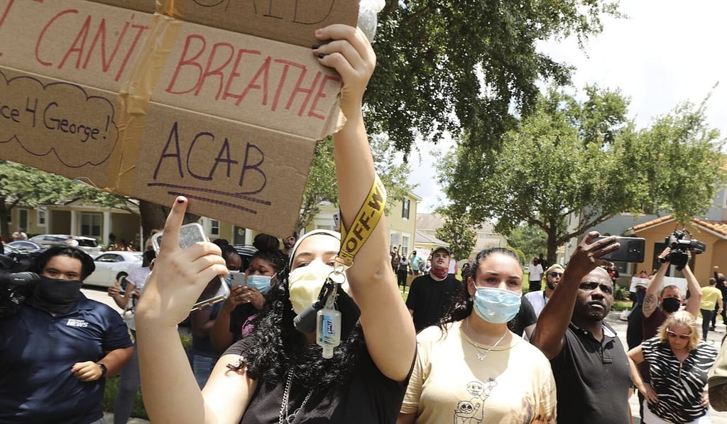 Protesters yell outside a home in Windermere, on Friday; “ACAB” stands for “all cops are b******s”. Photo: Orlando Sentinel via AP