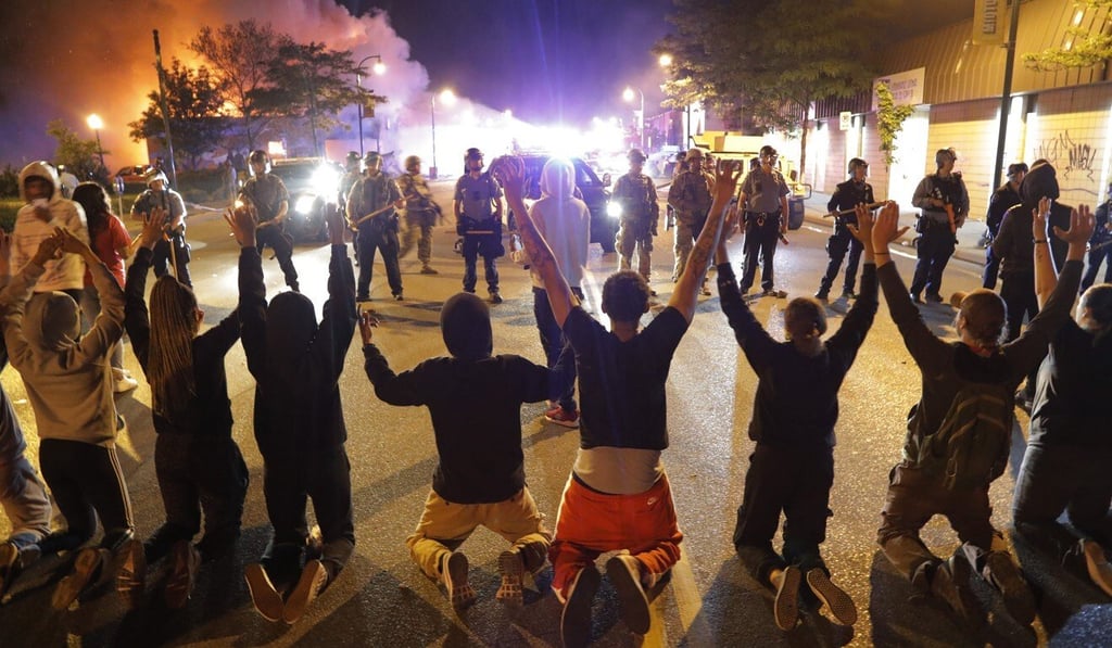 Demonstrators kneel before police in Minneapolis on Friday night. Photo: AP