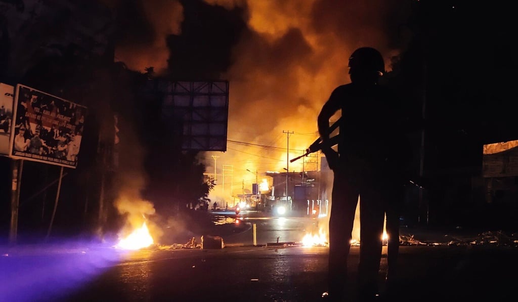 An armed policeman stands guard near a burning building after hundreds of demonstrators marched near Papua's biggest city Jayapura last August. Photo: AFP