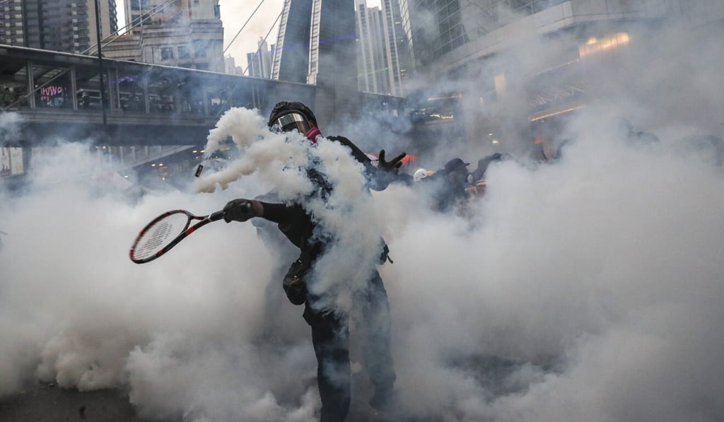 A protester uses a tennis racket to return a tear-gas canister in Hong Kong. Photo: Sam Tsang