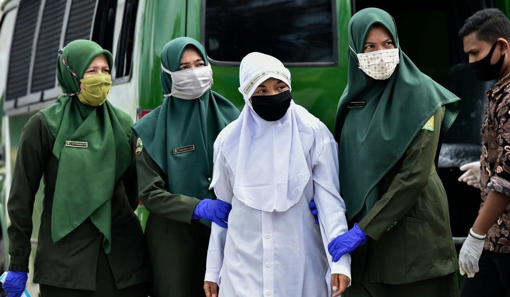 A woman is escorted by officials before receiving 100 whippings by religious police in Jantho, Aceh province. Photo: AFP
