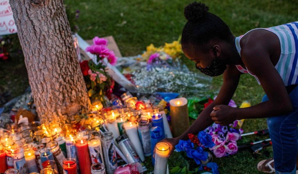 Honesty Strickland lights a candle during a vigil on Saturday around a makeshift memorial at the tree where Robert Fuller was found dead outside Palmdale City Hall. Photo: AFP