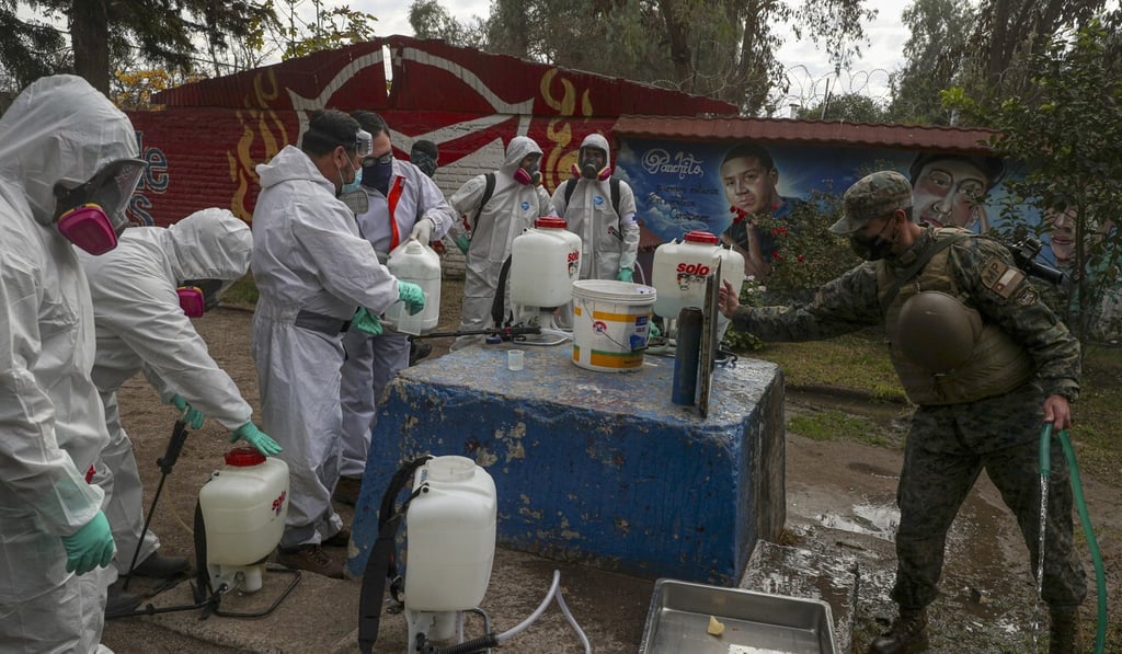 Soldiers in full protection gear prepare to disinfect an area in Maipu, on the outskirts of Santiago, Chile. Photo: AP