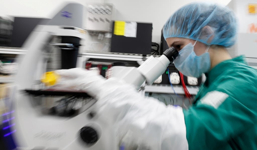 A scientist examines cells infected with Covid-19 under a microscope while researching a vaccine. Photo: Reuters A scientist examines cells infected with Covid-19 under a microscope while researching a vaccine. Photo: Reuters