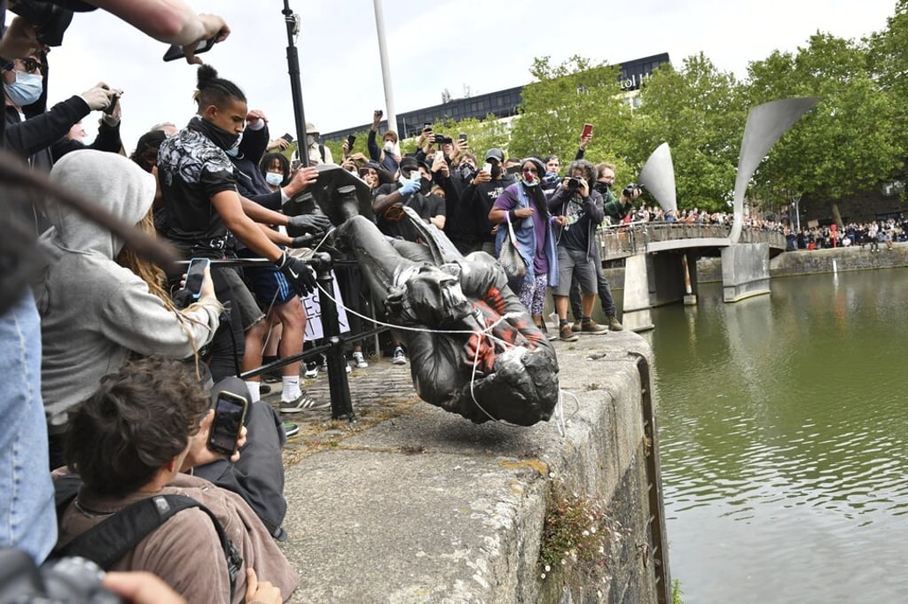 Protesters throw a statue of slave trader Edward Colston into Bristol harbour, in Britain, on June 7. Photo: AP Protesters throw a statue of slave trader Edward Colston into Bristol harbour, in Britain, on June 7. Photo: AP