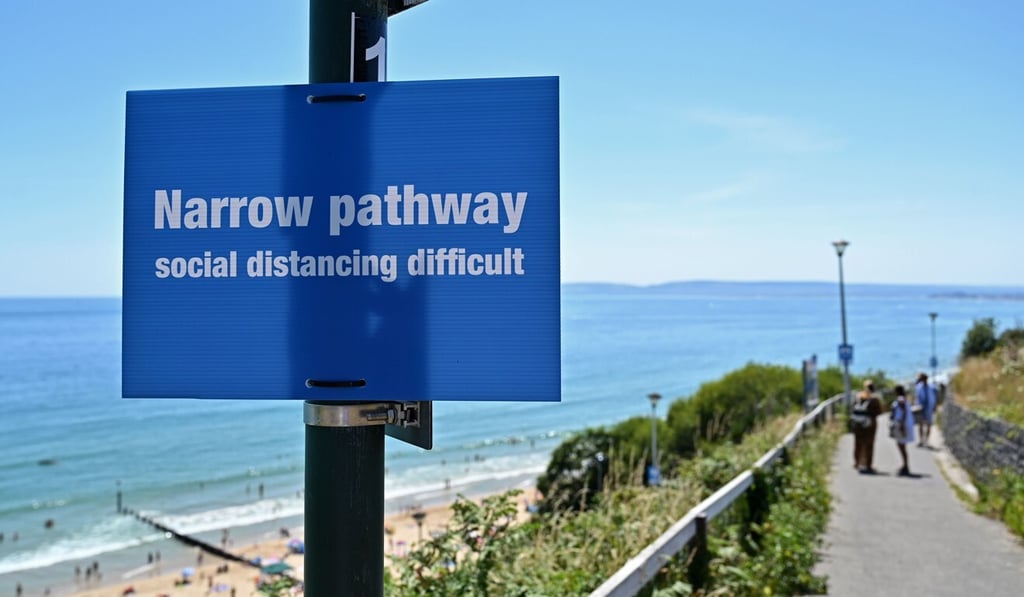 A sign tells beachgoers that adhering to the social distancing guidelines could be difficult on the narrow pathway near Bournemouth beach on Thursday. Photo: AFP A sign tells beachgoers that adhering to the social distancing guidelines could be difficult on the narrow pathway near Bournemouth beach on Thursday. Photo: AFP