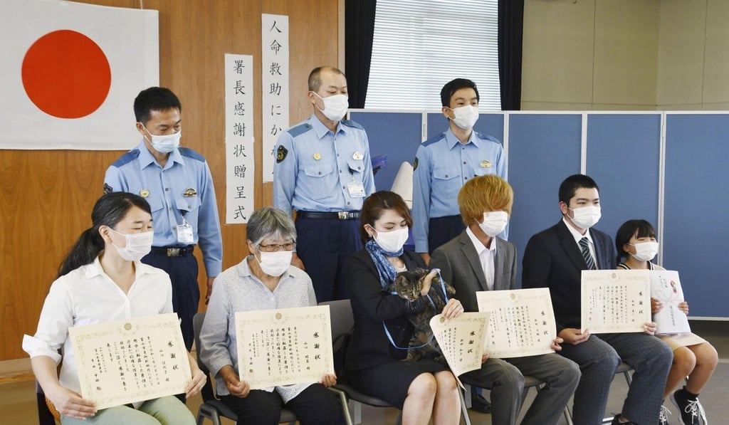 Tomoko Nitta and her cat Koko, along with four neighbours, receive an award at a police station in Toyama. Photo: Kyodo