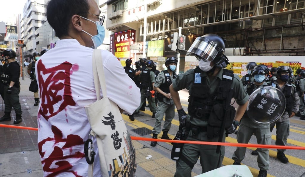 A man wearing a shirt reading “national security” in Chinese as riot police disperse protesters during a silent march in protest against the national security law in Hong Kong on June 28. (Picture: Dickson Lee/South China Morning Post)