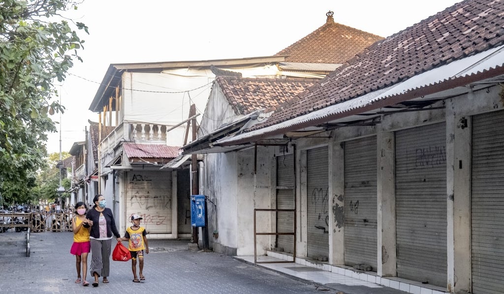 People walk past closed souvenir shops in Kuta, Bali, on June 29. Photo: EPA People walk past closed souvenir shops in Kuta, Bali, on June 29. Photo: EPA