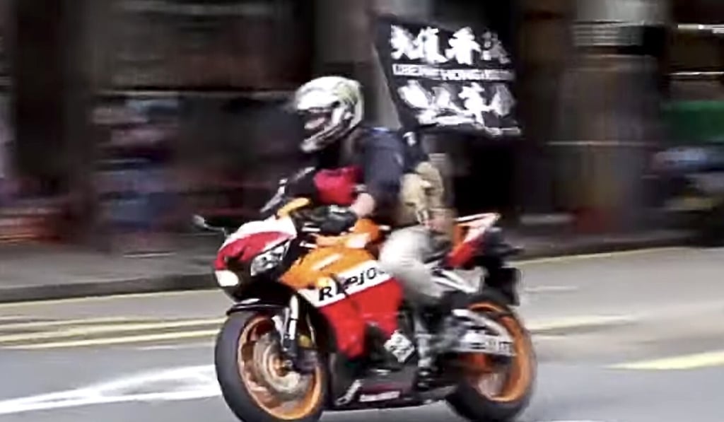 A 23-year-old man was taken into custody after he allegedly drove a motorbike with a flag bearing the slogan “Liberate Hong Kong; revolution of our times” into three police officers in Wan Chai on July 1. Photo: Cable TV