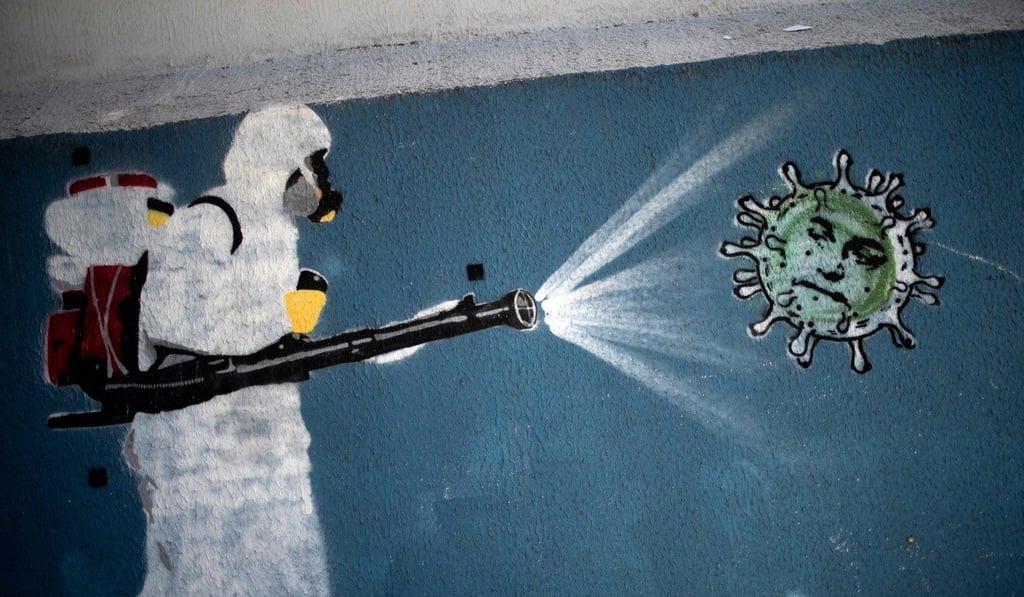 A mural in Rio de Janeiro depicts a man in protective suit spraying disinfectant on a coronavirus with Brazilian President Jair Bolsonaro's face. Photo: AFP