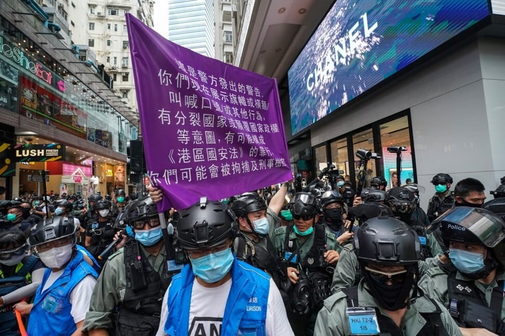 A police officer in riot gear holds up a purple flag warning anti-government protesters they could be violating the national security law during a demonstration on July 1. Photo: Felix Wong A police officer in riot gear holds up a purple flag warning anti-government protesters they could be violating the national security law during a demonstration on July 1. Photo: Felix Wong