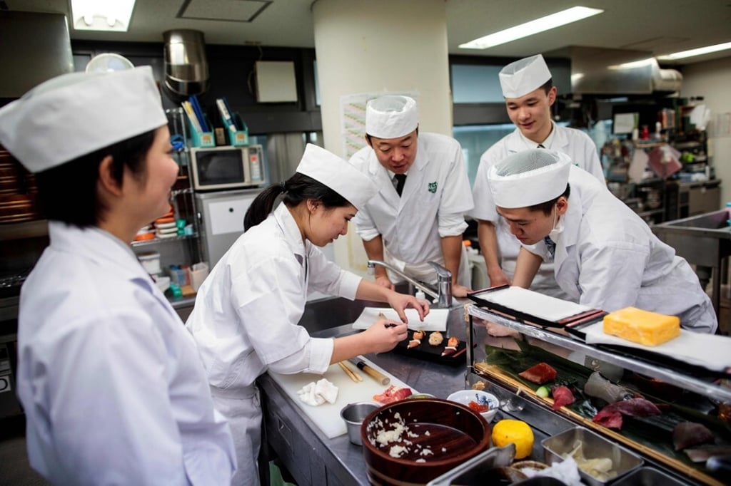 Two women are among several chefs training to become a sushi chef, traditionally a profession dominated by men, in a class in Tokyo in December 2019. As work opportunities grow for women, the fertility rate could further fall. Photo: AFP