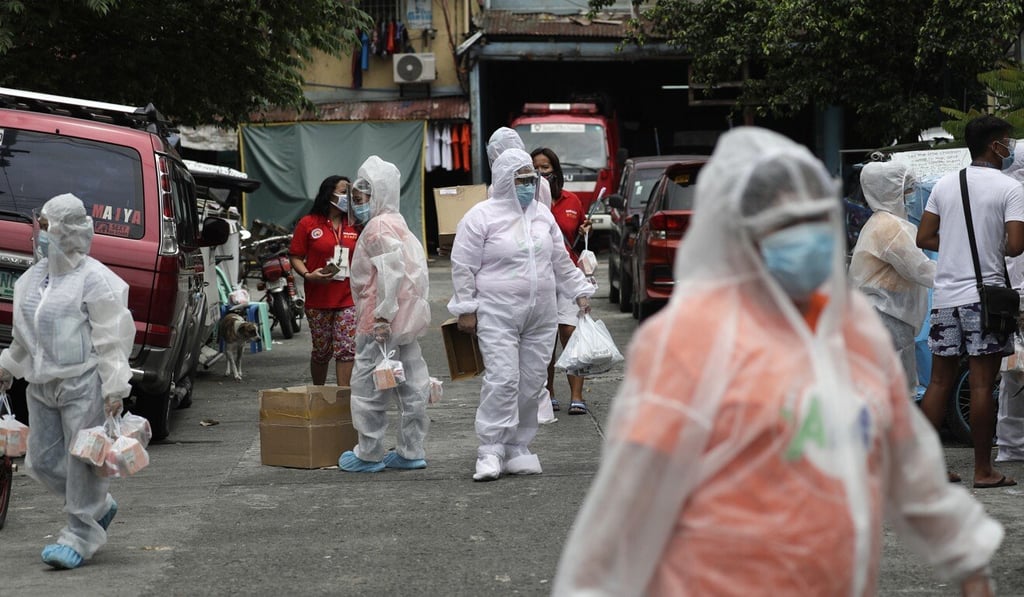 Health workers wearing protective suits distribute free medicines and vitamins to residents of Caloocan city in the Philippines. Photo: AP Health workers wearing protective suits distribute free medicines and vitamins to residents of Caloocan city in the Philippines. Photo: AP