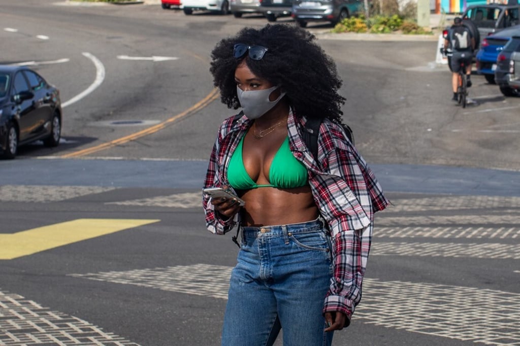 A woman wearing a face mask crosses the street in Hermosa Beach, California, the US. Scientists say masks can help reduce the severity of the disease caused by coronavirus even if you get infected by it. Photo: AFP