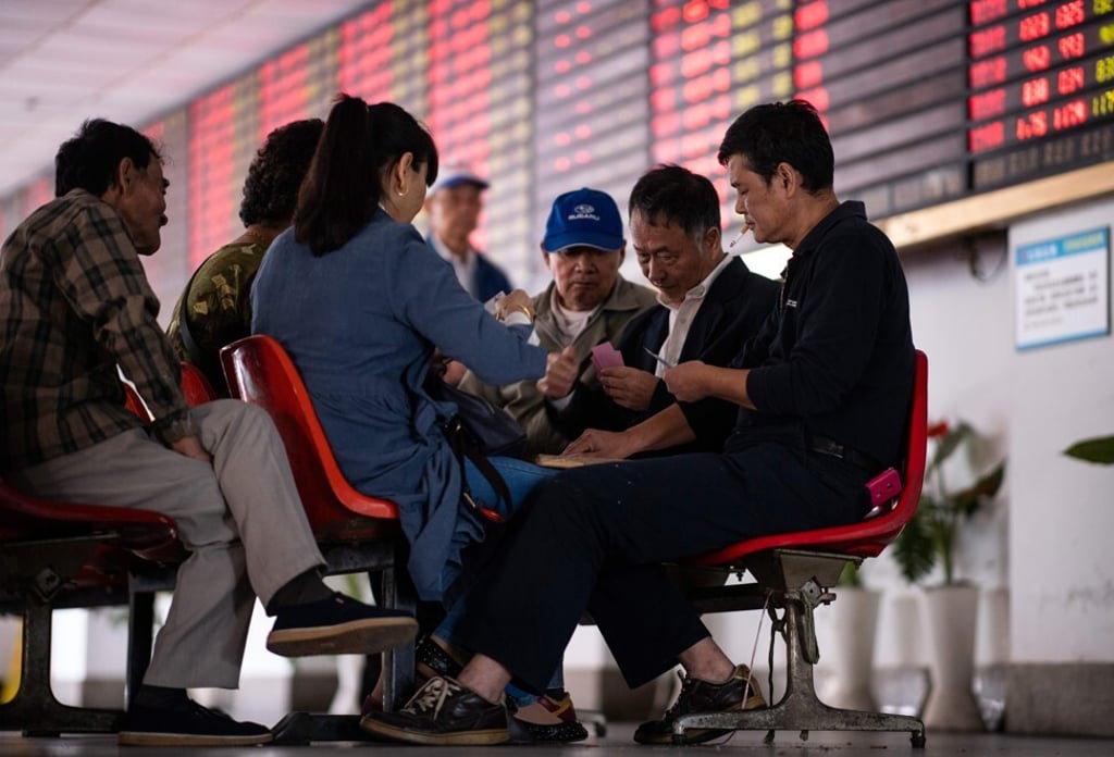 Investors playing cards in front of an electronic board showing stock information at a brokerage house in Shanghai on October 15, 2018, an enduring and common scene in thousands of brokerages across the country. Photo: AFP