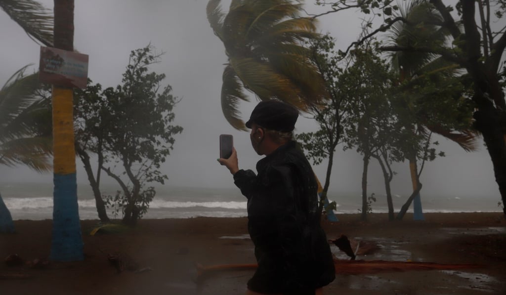 A woman uses her phone to record strong waves caused by Tropical Storm Laura in southern Puerto Rico on Saturday. Photo: EPA-EFE