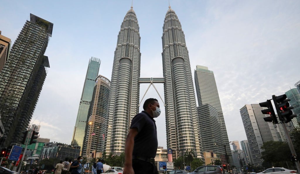 A man wearing a protective mask crosses a street in front of the Petronas Twin Towers, in Kuala Lumpur. Photo: Reuters A man wearing a protective mask crosses a street in front of the Petronas Twin Towers, in Kuala Lumpur. Photo: Reuters