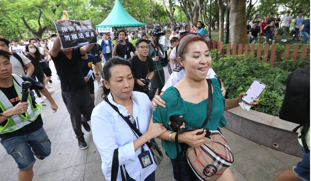 A police officer leads a woman from mainland China out of Tuen Mun Park during a protest organised by local residents last year. Photo: Felix Wong A police officer leads a woman from mainland China out of Tuen Mun Park during a protest organised by local residents last year. Photo: Felix Wong