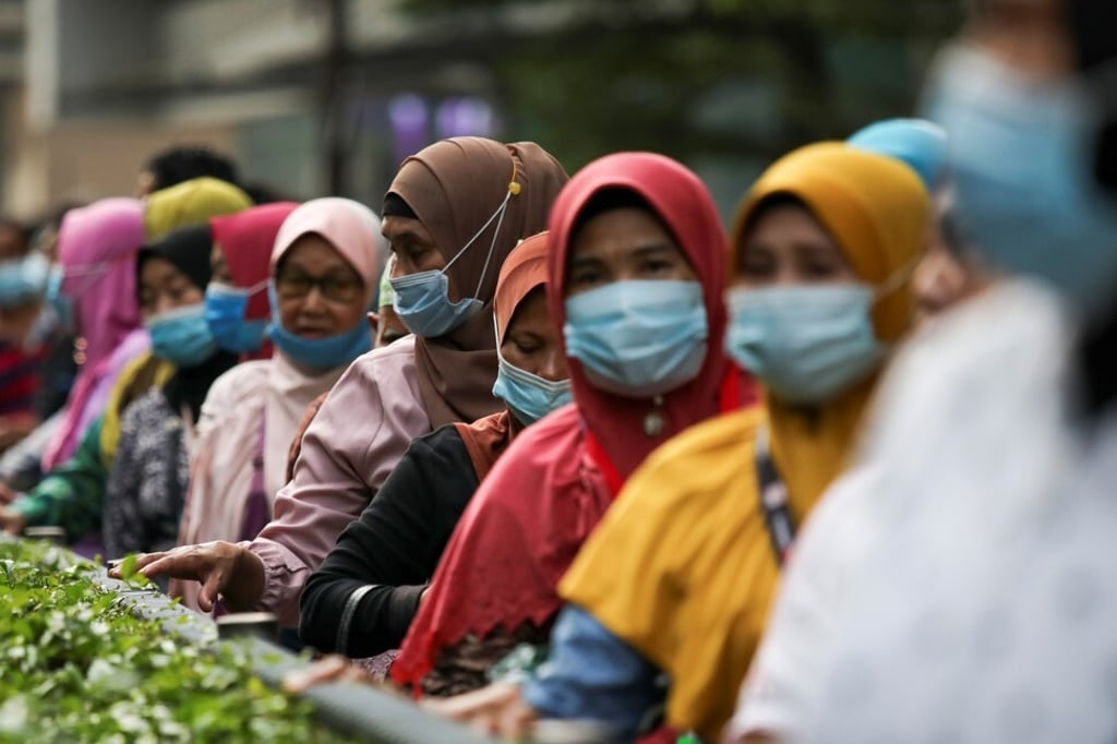 Passengers wearing protective masks wait in line at a bus station in Kuala Lumpur. Photo: Reuters