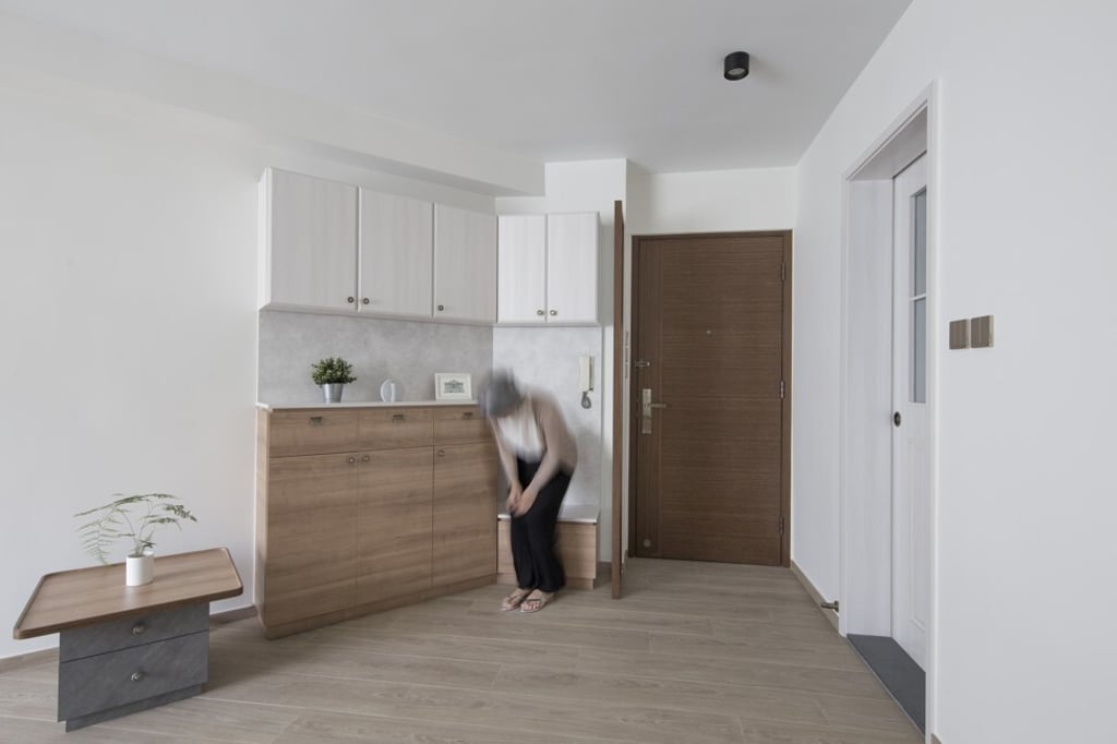 The interior of a flat redesigned by Patrick Lam, founder of Sim-Plex Design Studio, incorporates rounded corners on furniture, and a shoe cabinet in the entrance area that provides a sturdy seat with storage underneath.