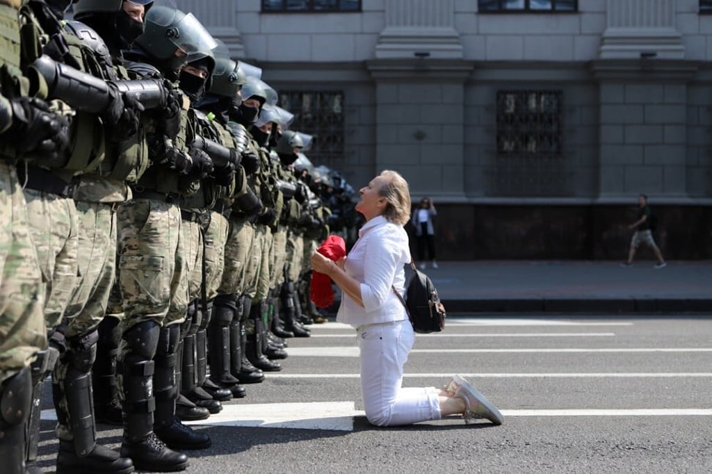A woman kneels in front of a riot police line as they block Belarusian opposition supporters rally in the centre of Minsk. Photo: AP
