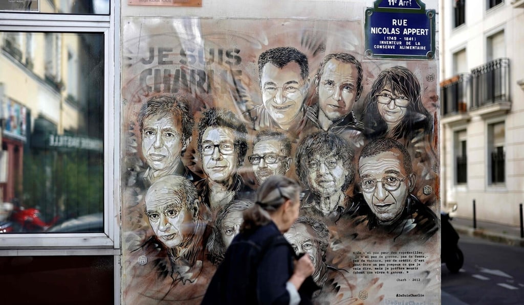 A woman walks past a painting in Paris by French street artist Christian Guemy, known as C215, in tribute to those killed in the Charlie Hebdo attack. Photo: AFP