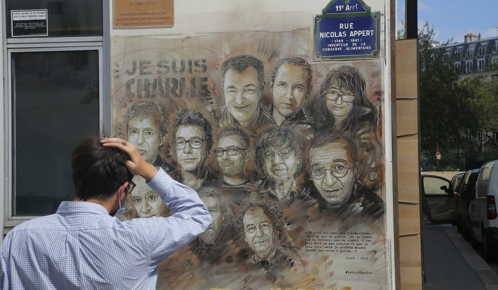 A man looks at a painting by French street artist Christian Guemy, also known as C215, in Paris on Wednesday, in tribute to the Charlie Hebdo staff killed in a 2015 attack. Photo: AP
