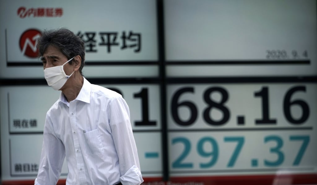 A man wearing a face mask walks past an electronic stock board showing Japan’s Nikkei 225 index. Photo: AP A man wearing a face mask walks past an electronic stock board showing Japan’s Nikkei 225 index. Photo: AP