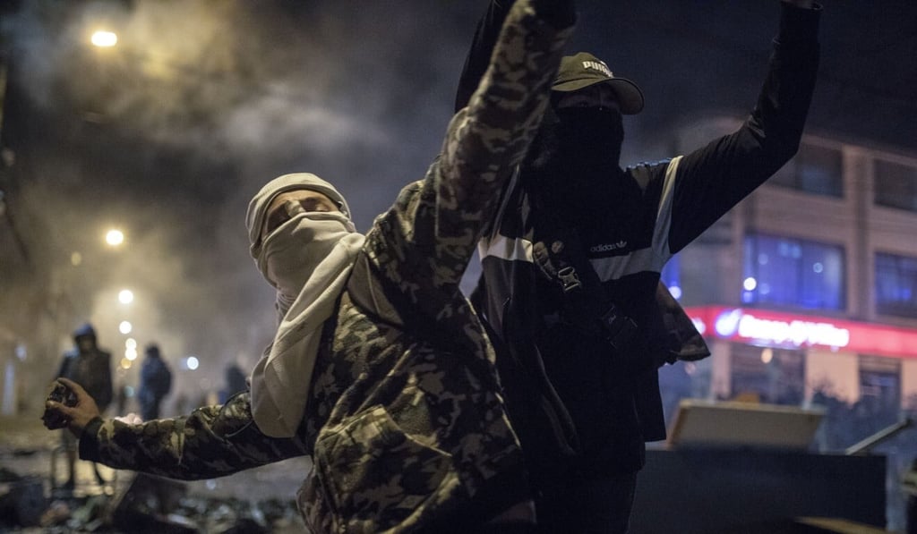 A masked and hooded man hurls stones at police during protests in Bogota on Wednesday. Photo: AP