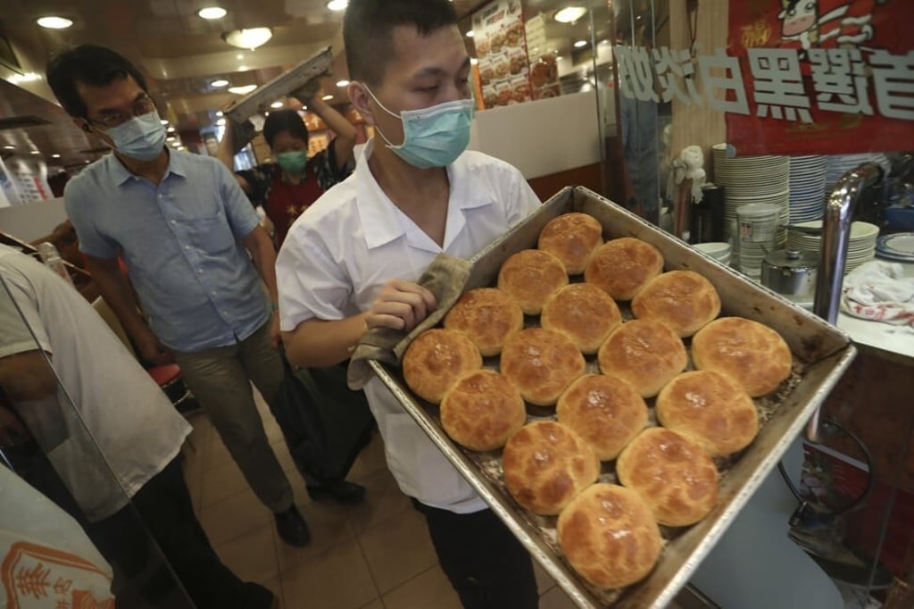 A waiter carries a tray of freshly cooked pineapple buns at Kam Wah Cafe in Mong Kok. Photo: Jonathan Wong