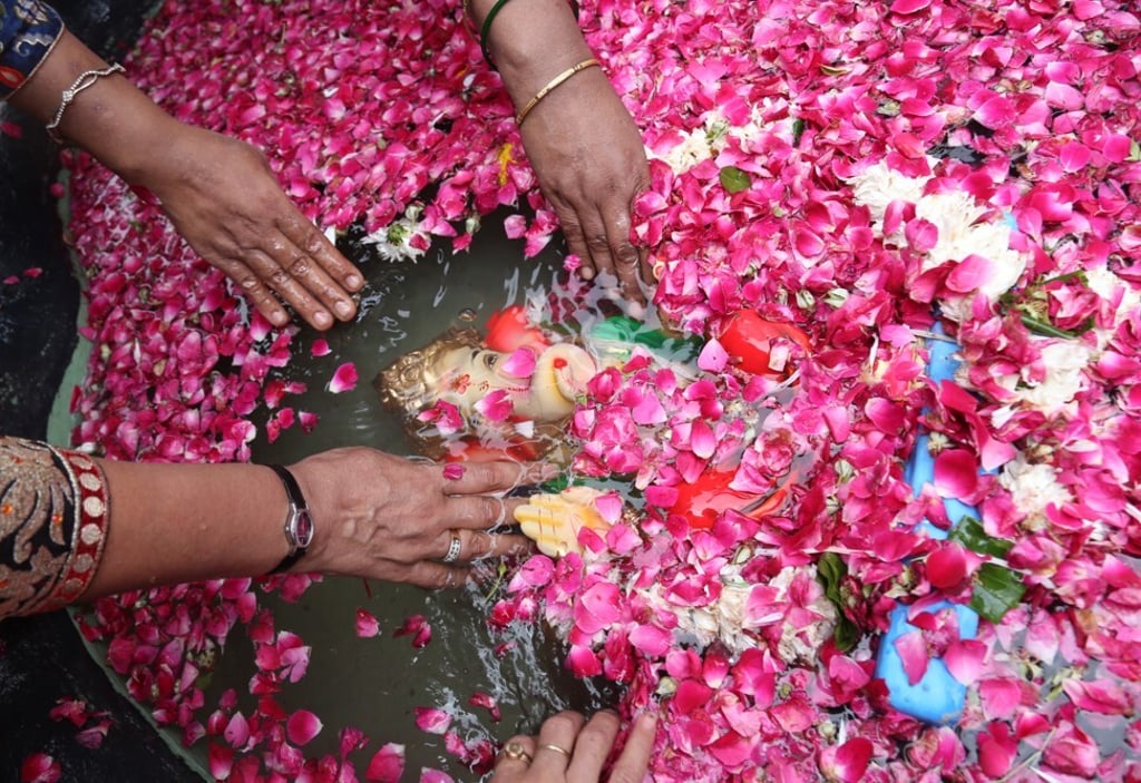 An idol of Ganesh is immersed by devotees in a tub at their home in Delhi. Photo: Amarjeet Kumar Singh