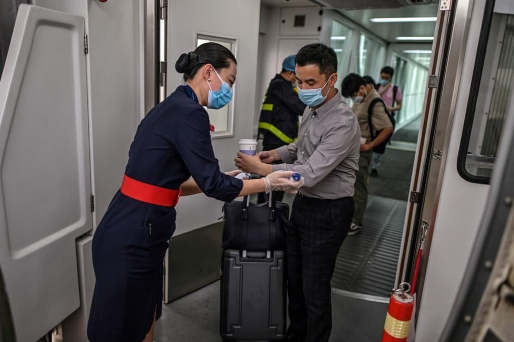 A flight attendant checks the body temperature of passengers as they board. Photo: AFP