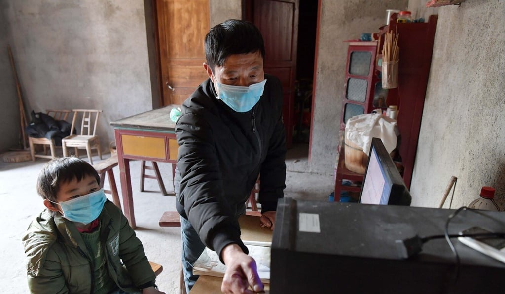 Luo Changshi (right), the headmaster of Xinzhu Elementary School, downloads online courseware for his student Guo Shiqian in Xinzhu Village, Jiangxi Province, in February. Picture: Xinhua Luo Changshi (right), the headmaster of Xinzhu Elementary School, downloads online courseware for his student Guo Shiqian in Xinzhu Village, Jiangxi Province, in February. Picture: Xinhua