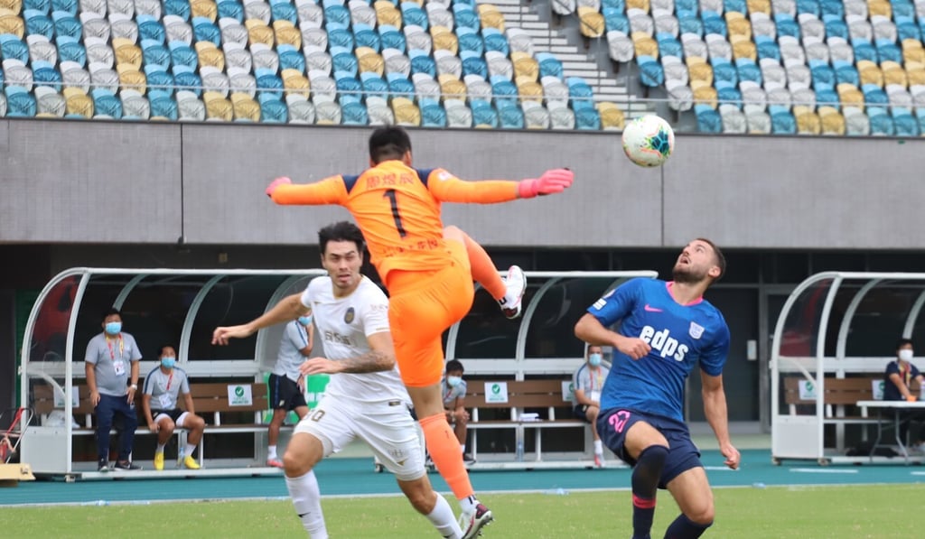 R&F goalkeeper Zhou Yuchen attempts to clear the ball ahead of Kitchee striker Gavilan Manu. R&F goalkeeper Zhou Yuchen attempts to clear the ball ahead of Kitchee striker Gavilan Manu.