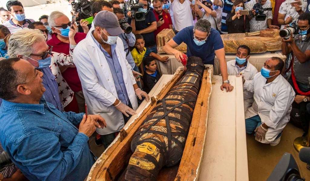 Egyptian Minister of Tourism and Antiquities Khaled Al-Anani, right, and Mustafa Waziri, Secretary General of the Supreme Council of Antiquities, left, unveil the mummy inside a sarcophagus excavated at the Saqqara necropolis. Photo: AFP