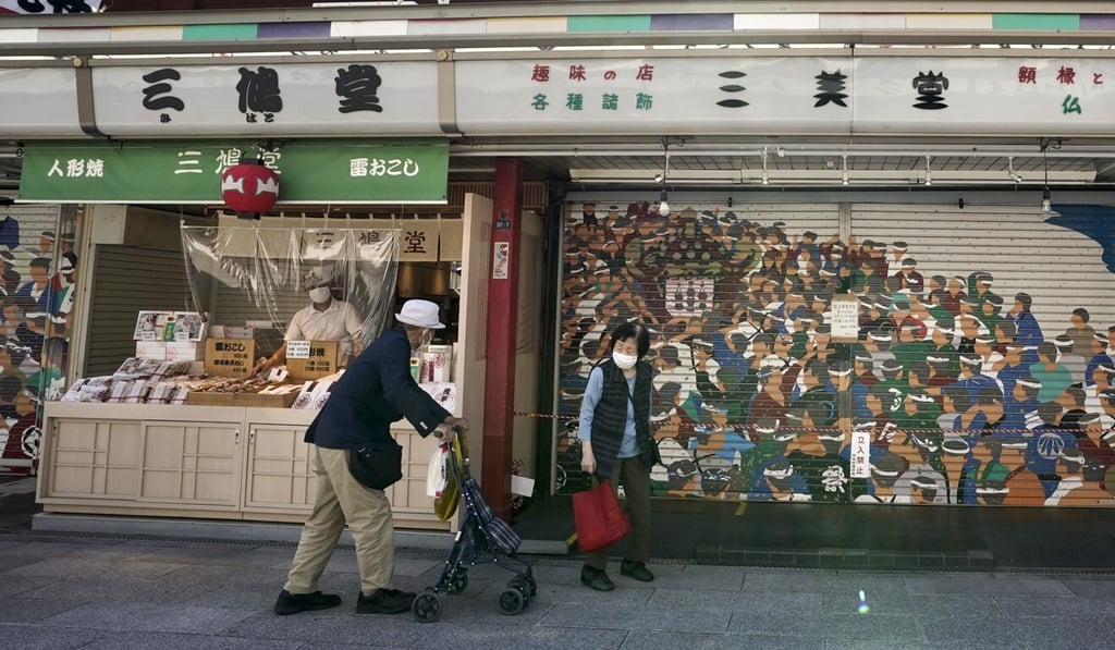 An elderly couple walk along a street in Tokyo in May. Photo: EPA