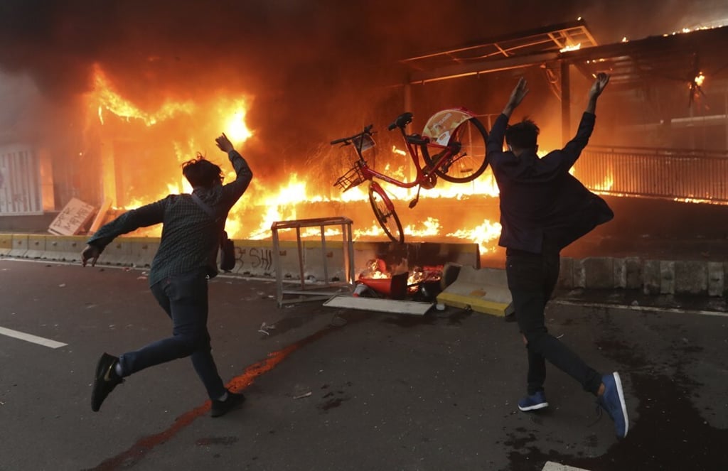 Protesters add a bicycle to a burning metro station during a demonstration in Jakarta. Photo: AP Protesters add a bicycle to a burning metro station during a demonstration in Jakarta. Photo: AP