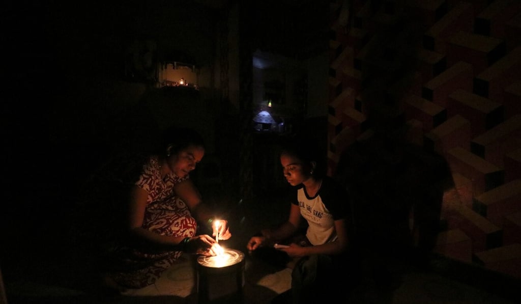 A woman and her daughter light a candle inside their house after a power outage in Mumbai. Photo: Reuters