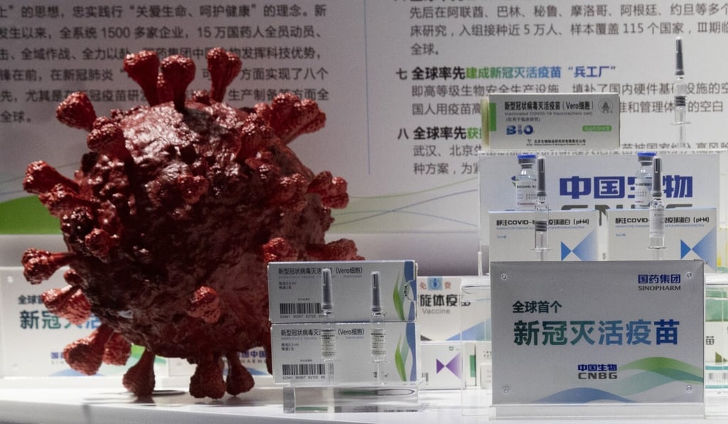 Samples of a Covid-19 vaccine are displayed near a 3D model of a coronavirus during a trade fair in Beijing last month. Photo: AP