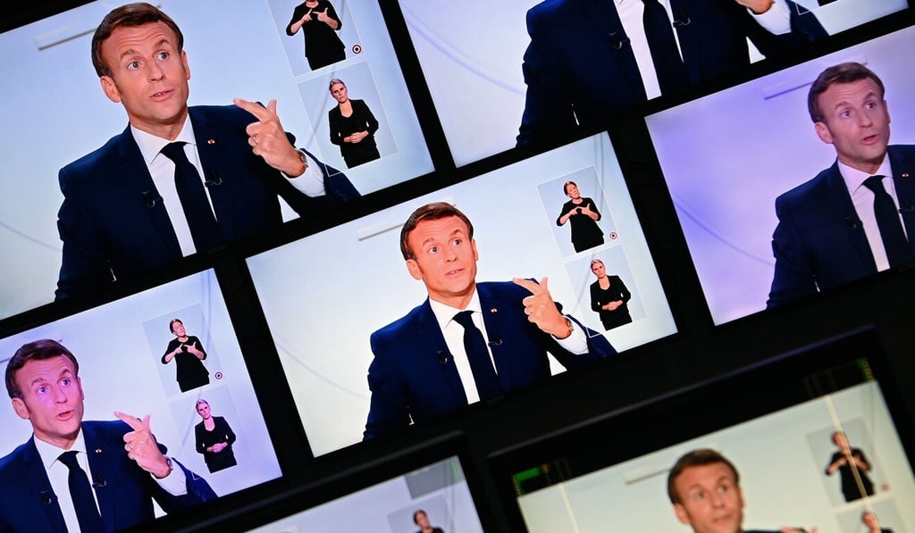 French President Emmanuel Macron appears on a wall of screens in Paris as he addresses the nation during a televised interview on Wednesday. Photo: AFP