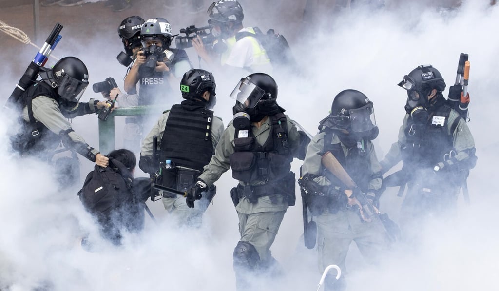 Police in riot gear move through a cloud of smoke as they detain a protester at the Hong Kong Polytechnic University in November. Photo: AP