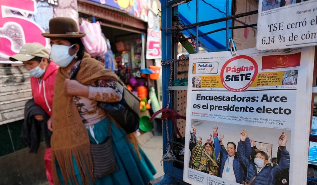 Two women walk past a newspaper stand with a headline reading “Pollsters: Arce is the president-elect” in La Paz, Bolivia on Monday. Photo: Reuters