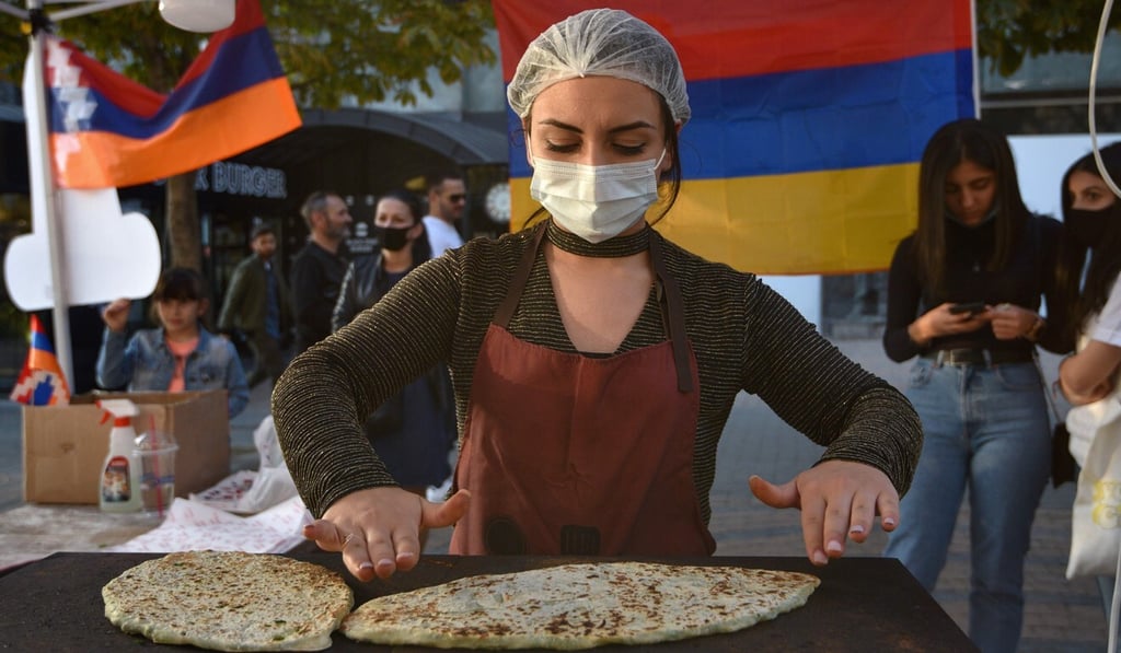 Refugee women who fled Nagorno-Karabakh make jingalov hats – traditional Karabakh flatbreads stuffed with greens – for sale in Yerevan on Monday. The money raised will be sent to Karabakh. Photo: AFP