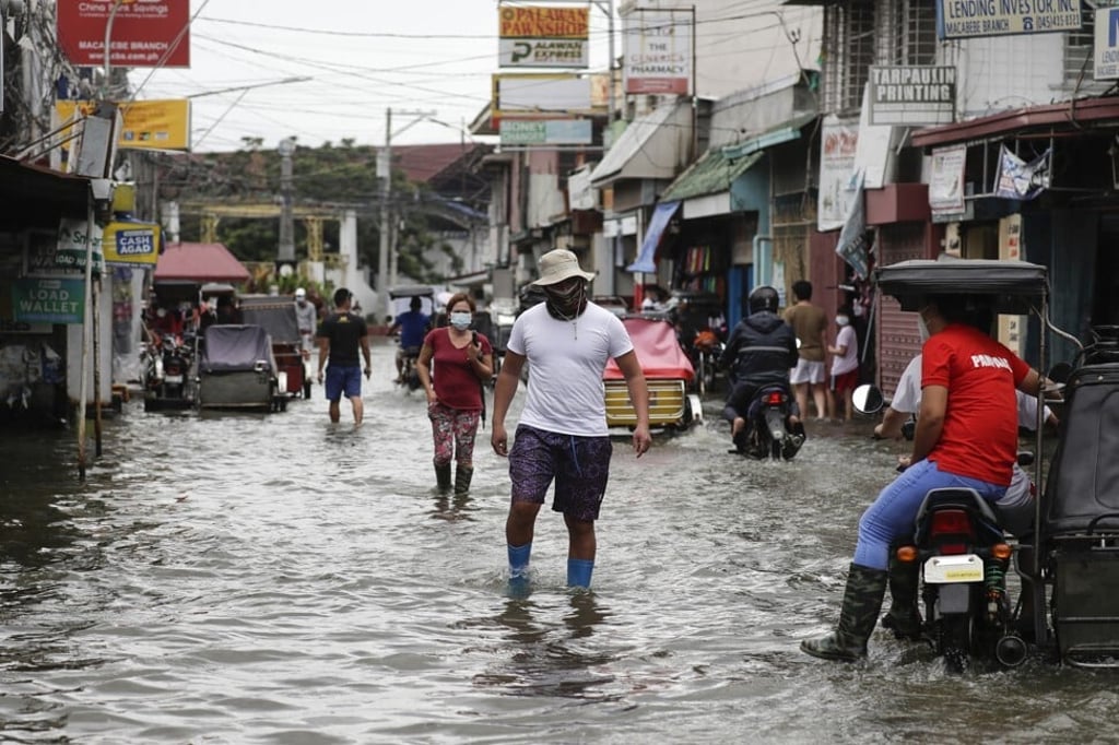 Residents wearing masks wade through a flooded road from Typhoon Molave in Pampanga province, northern Philippines. Photo: AP
