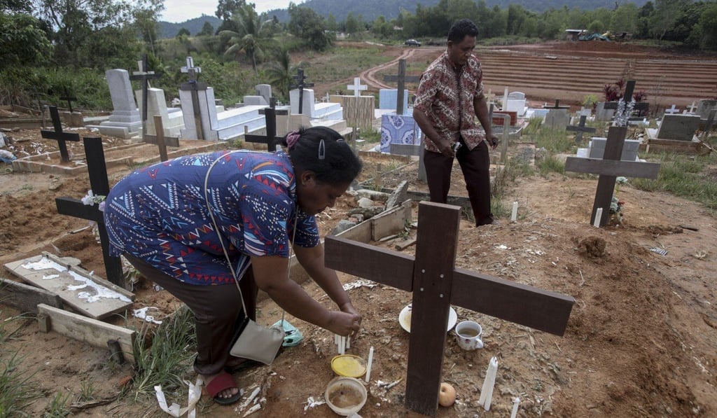 An Indonesian migrant worker places candles on the grave of her husband who worked on a Malaysian palm oil plantation in 2018. As global demand for palm oil surges, plantations are struggling to find enough labourers, frequently relying on brokers who prey on the most at-risk people. The bodies of migrants who die are sometimes not sent home. Photo: AP