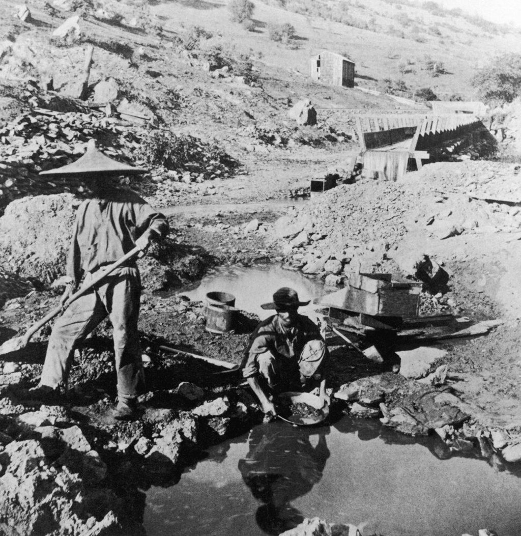 A Chinese worker in a coolie hat digs as another kneels and pans for gold in California circa 1855. Photo: Getty Images A Chinese worker in a coolie hat digs as another kneels and pans for gold in California circa 1855. Photo: Getty Images