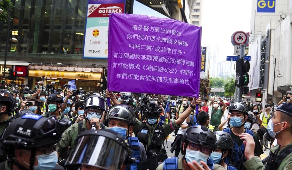 Police officers raise a purple flag warning of potential national security law violations in Causeway Bay. Photo: Sam Tsang Police officers raise a purple flag warning of potential national security law violations in Causeway Bay. Photo: Sam Tsang